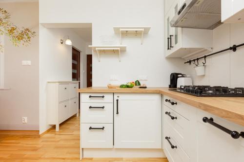 a kitchen with white cabinets and a wooden counter top at Apartment Grzybowska by Renters in Warsaw