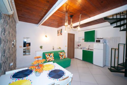 ナポリにあるBianca Napoli Suiteのキッチン(白いテーブル、緑のソファ付)