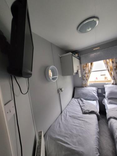 een kleine kamer met 2 bedden en een televisie bij Cairnryan Heights 2 Bed caravan holiday home in Stranraer