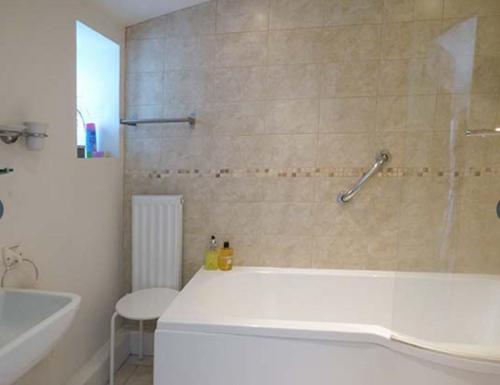 a white bathroom with a tub and a shower at Rectory Cottage in Abergavenny