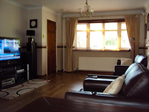 sala de estar con sofá y TV en Birchwood Private Room for Homestay, en Risley