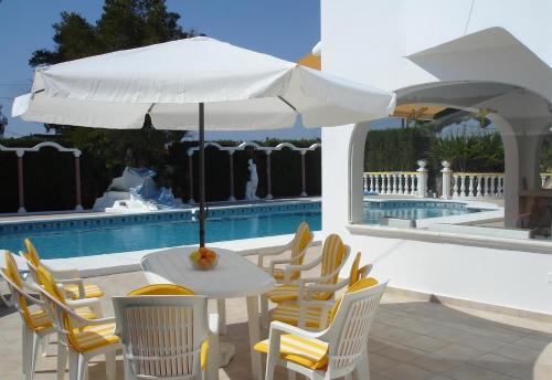 una mesa con sombrilla y sillas junto a una piscina en Casa in Calpe Carrio Park, en Calpe