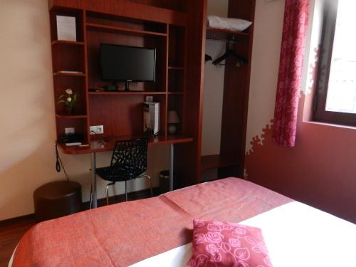 a bedroom with a bed and a desk with a television at L'HÔTEL de CHARTRES in Chartres