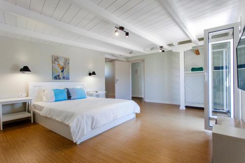 a white bedroom with a large white bed and wooden floors at Ligia Waterfront Apartments in Lygia