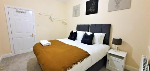 a bedroom with a large bed with blue pillows at Shakespeare Views - Modern Northampton Apartment in Northampton