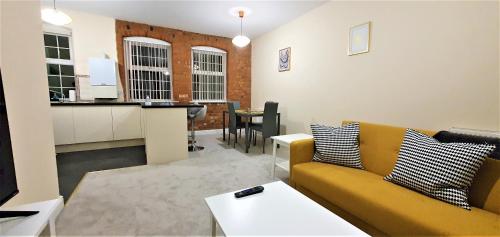 a living room with a yellow couch and a kitchen at Shakespeare Views - Modern Northampton Apartment in Northampton