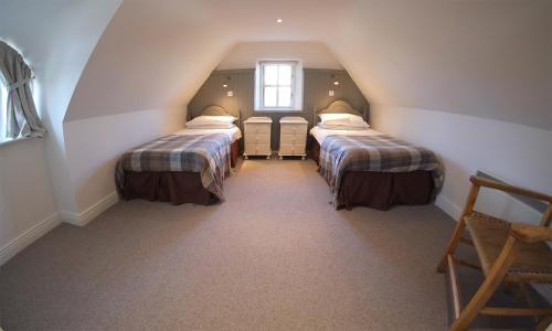 a attic room with two beds and a window at Ballyvaughan Cottages in Ballyvaughan