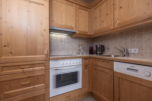 a kitchen with wooden cabinets and a white stove top oven at Wellnessappartements Margit in Alpbach
