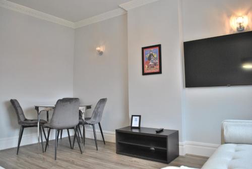 a living room with a table and chairs and a television at Trafford Terrace Davyhulme in Urmston