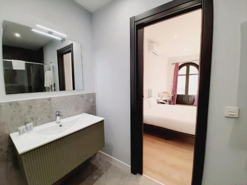 een badkamer met een wastafel, een spiegel en een bed bij Apartamentos Vega by gaiarooms in Salamanca