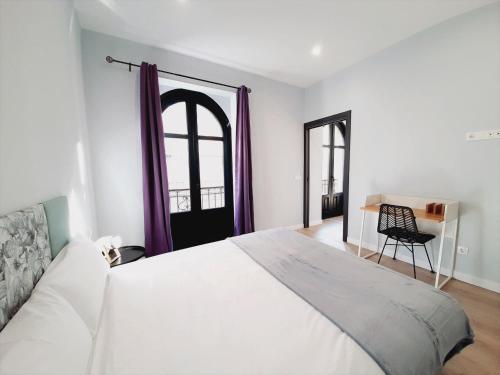 sypialnia z dużym białym łóżkiem i krzesłem w obiekcie Apartamentos Vega by gaiarooms w Salamance
