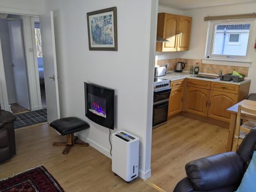 a kitchen with a living room with a tv and a table at The Little Houses in Roybridge