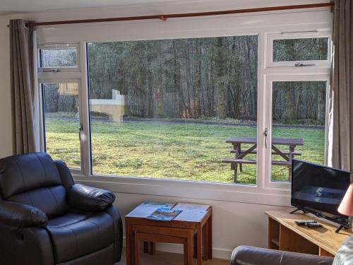 a living room with a window and a chair and a table at The Little Houses in Roybridge