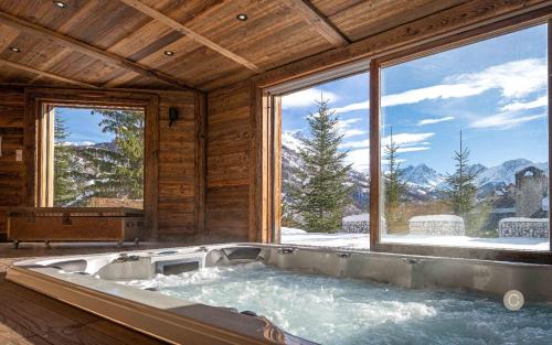 a bath tub in a room with a large window at L'Or des Cimes in Valloire