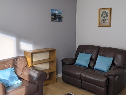 a living room with a brown leather couch and blue pillows at The Little Houses in Roybridge