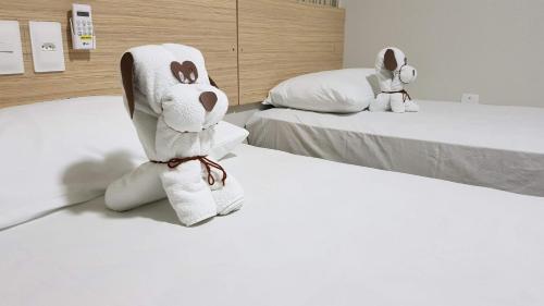 two stuffed animals are sitting on two beds at Max Hotel in Arcoverde