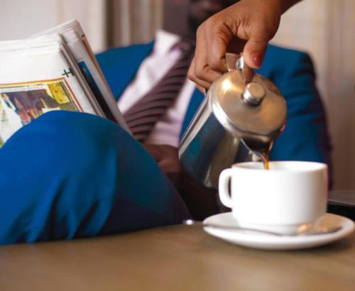 a person pouring coffee into a cup on a table at The Swiss Hotel Freetown in Freetown