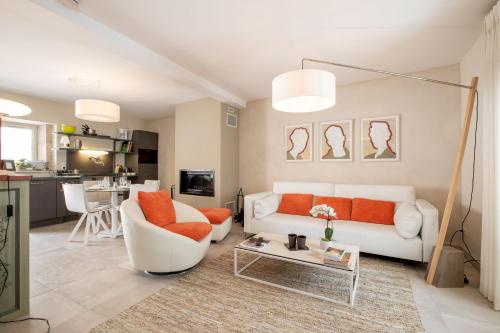 - un salon avec un canapé blanc et des oreillers orange dans l'établissement Les Demeures du Tonnelier, Maison Côté Jardin, à Saint-Romain