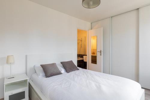 - une chambre blanche avec un lit blanc et un miroir dans l'établissement DIFY Palais - Cordeliers, à Lyon