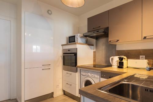 une cuisine avec un évier et une cuisinière four supérieur dans l'établissement DIFY Palais - Cordeliers, à Lyon