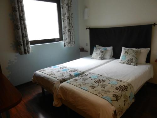 a bedroom with two beds and a window at L'HÔTEL de CHARTRES in Chartres