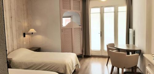 a room with two beds and a table and a window at Résidence du Bois de Lon in Lamalou-les-Bains