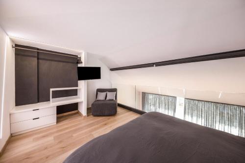 a bedroom with a bed and a tv and a chair at Appartamento Mazzin in Mazzin
