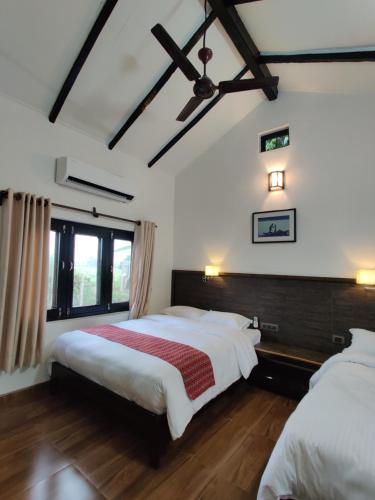 Duas camas num quarto com paredes brancas e pisos em madeira em Bardia Forest Resort em Bardia