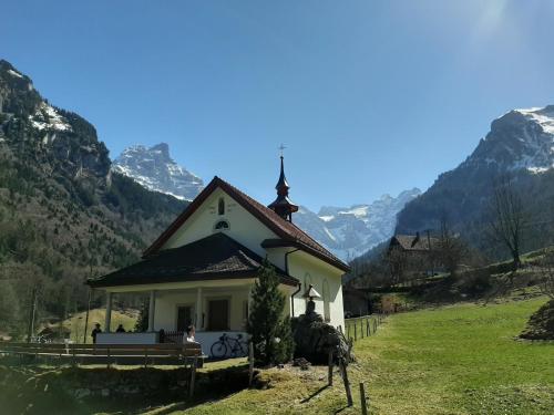 a small church on a hill with mountains in the background at Hotel Urirotstock in Isenthal
