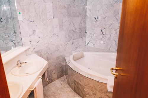 a bathroom with a white tub and a sink at Paul's Hotel in Knittelfeld