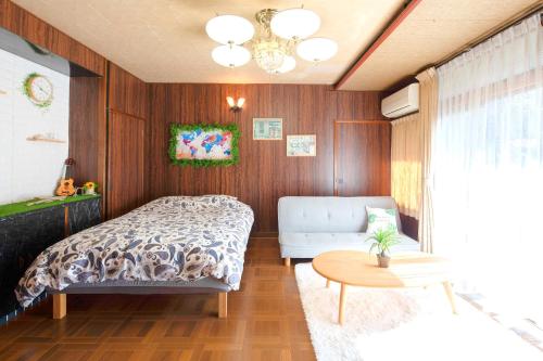 a bedroom with a bed and a couch and a table at Wぴーす（W PEACE) in Fukuchiyama