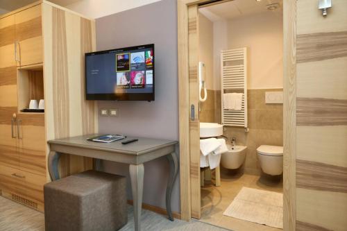 a bathroom with a sink and a toilet and a tv on the wall at Hotel Garden in Peschiera del Garda