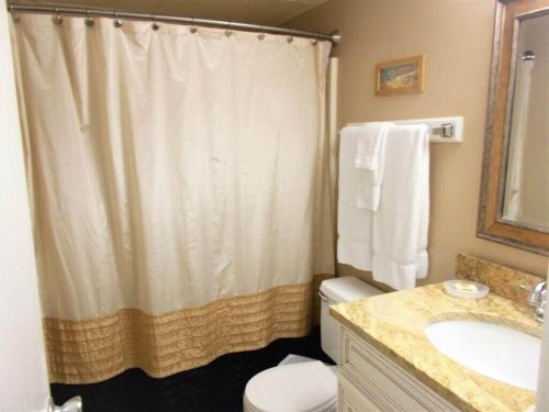 a bathroom with a shower curtain and a toilet and a sink at Gulf Shores Island Winds East #103, Gulf Front. Closest building to Hangout! in Gulf Shores
