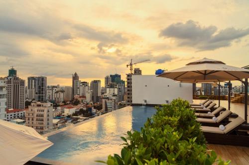 a rooftop pool with chairs and an umbrella and a city at OCEAN HOTEL in Phnom Penh