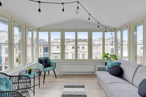 uma sala de estar com um sofá, cadeiras e janelas em Grand Apartments - City Centre Apartment em Sopot