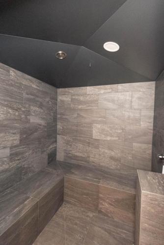 a bathroom with a large shower with wooden tiles at Boutique Hotel Edelweiss in Sankt Anton am Arlberg