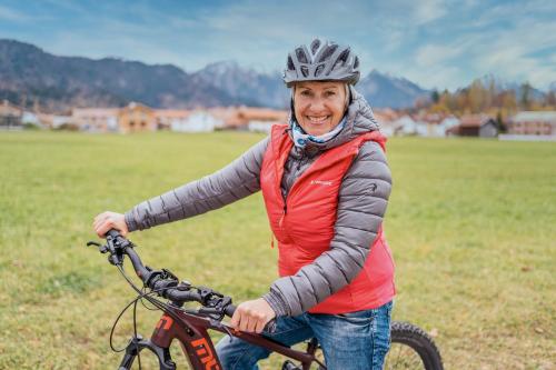 a woman is holding a bike in a field at Hotel Sommer - Urlaubs- und Wellnesshotel in Füssen