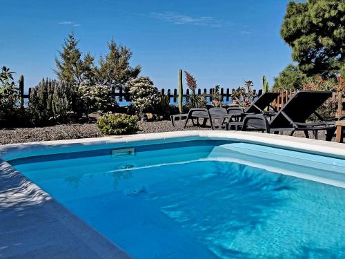 a swimming pool in a yard with chairs and trees at Fide in Tijarafe