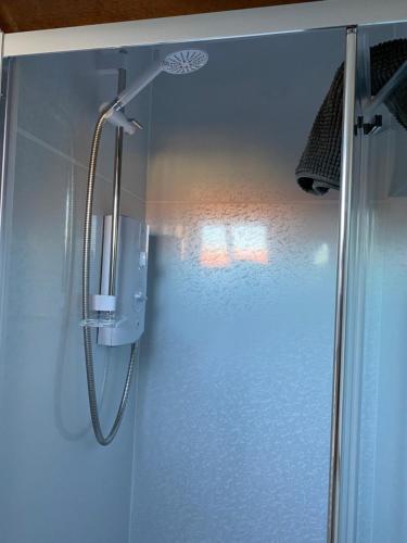 een douche met een glazen deur in een badkamer bij The Hayloft Cottage in Whitby