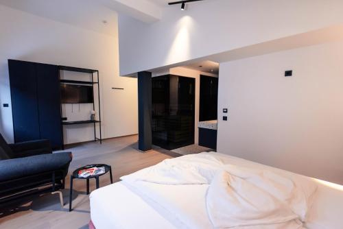 a bedroom with a white bed and a black chair at Boutique Hotel Edelweiss in Sankt Anton am Arlberg
