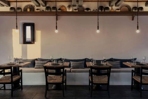 a dining room with tables and chairs and a couch at Kalesma Mykonos in Ornos