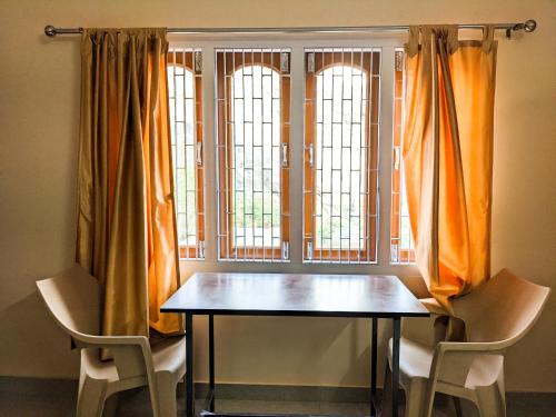 a table and two chairs in front of a window at Nilachal Homes in Guwahati