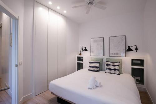 a bedroom with a large white bed with a ceiling fan at Stylish 2 Bedroom Apartment in the Heart of Madrid in Madrid