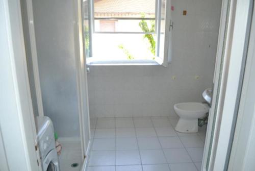 La salle de bains blanche est pourvue de toilettes et d'une fenêtre. dans l'établissement Appartamento 5, à Ameglia