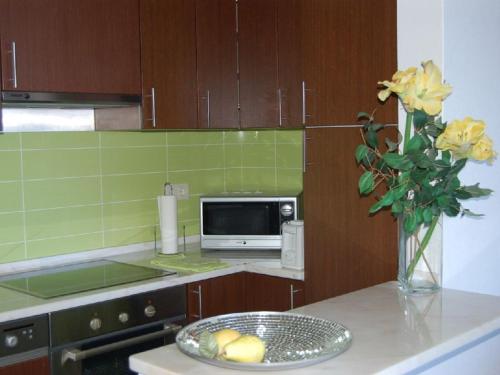 uma cozinha com um balcão com um vaso de rosas amarelas em Apartamento a 10 metros da praia de Albufeira em Albufeira