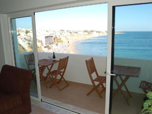 een balkon met een tafel en stoelen en de oceaan bij Apartamento a 10 metros da praia de Albufeira in Albufeira