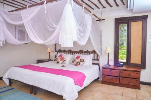 a bedroom with a large bed with a canopy at Jacaranda Indian Ocean Beach Resort in Diani Beach
