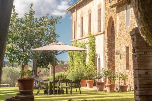 a patio with tables and chairs and an umbrella at Tenuta di Poggio Cavallo in Istia dʼOmbrone