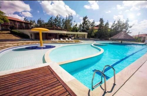 ein großer Swimmingpool mit einem gelben Sonnenschirm in der Unterkunft Flats family in Gravatá