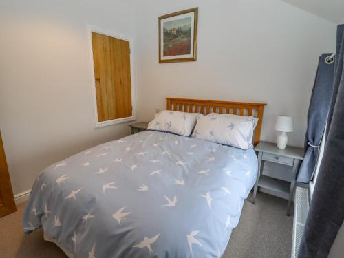 a bedroom with a bed with a blue bedspread with birds on it at Belvedere in Cinderford